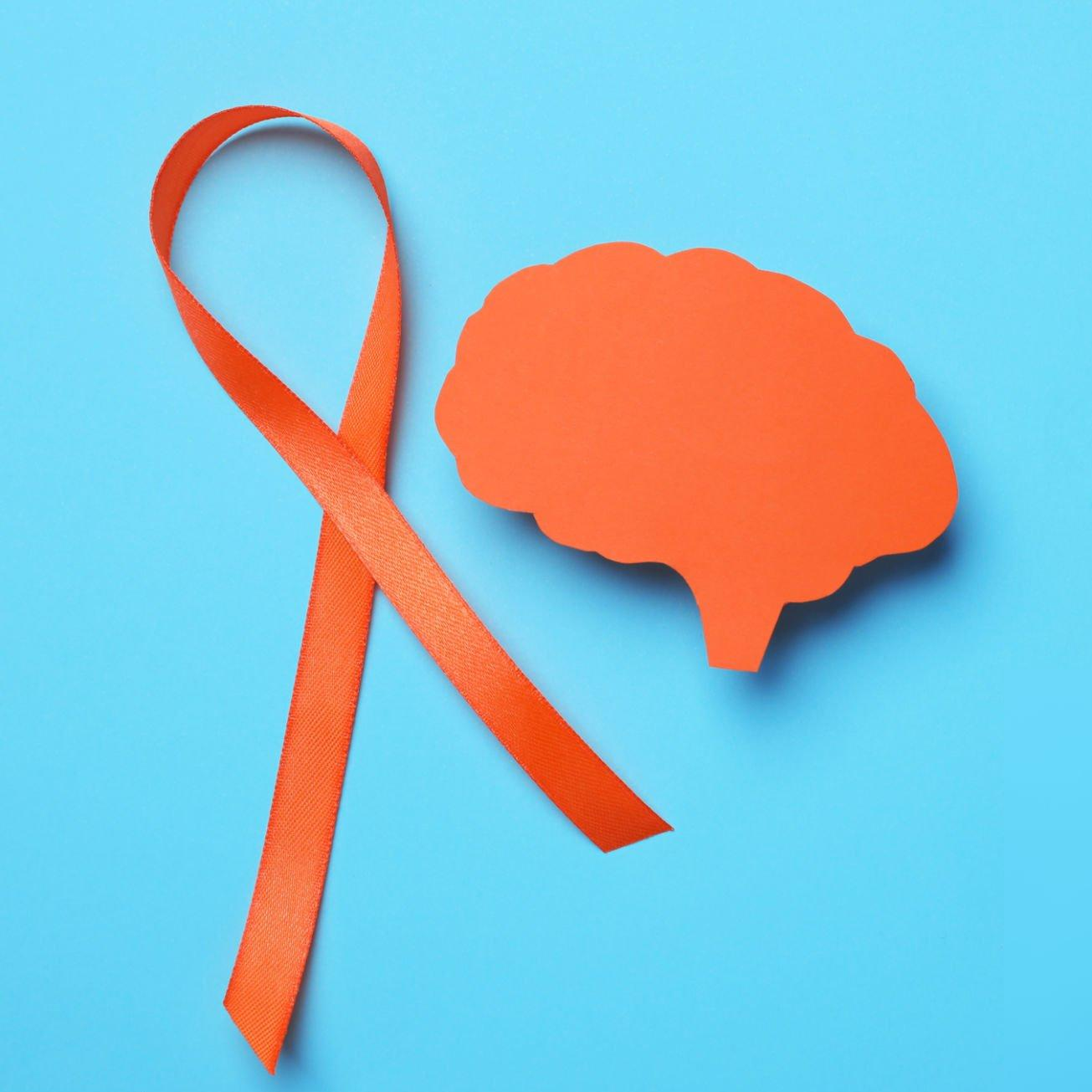 Orange ribbon and paper brain cutout for Multiple Sclerosis awareness.