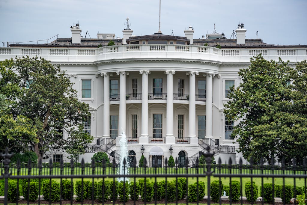 A classic view of the White House in Washington DC with lush greenery and fountains.